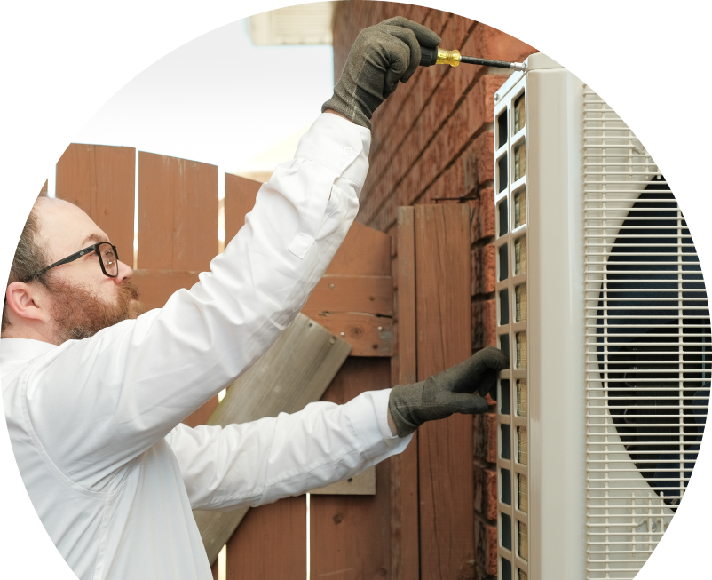 Anchor Home Comfort service personnel working on an AC condenser, using a screwdriver to secure the unit’s panel outdoors beside a wooden fence. Anchor Home Comfort service personnel working on an AC condenser, using a screwdriver to secure the unit's panel outdoors beside a wooden fence.