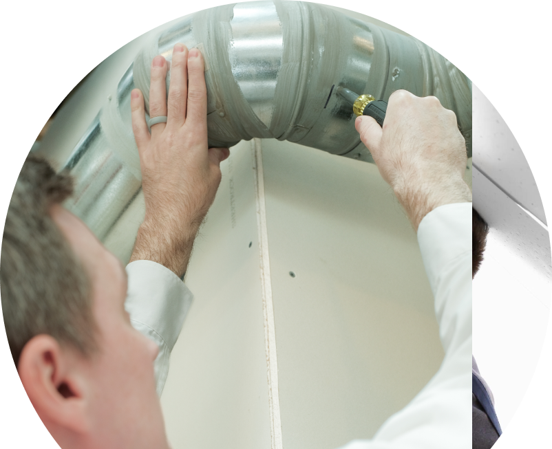 Anchor Home Comfort HVAC technician inspecting and tightening a joint on a sealed metal air duct, performing maintenance work during an air duct cleaning task. Anchor Home Comfort HVAC technician inspecting and tightening a joint on a sealed metal air duct, performing maintenance work during an air duct cleaning task.