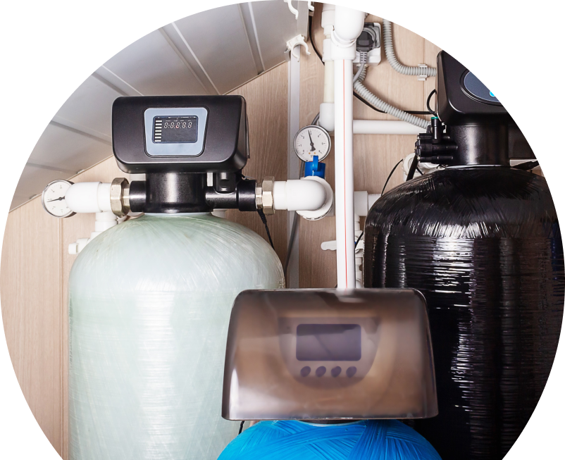 Anchor Home Comfort home water filtration system featuring resin tanks, digital control heads, pressure gauges, and connected piping in a utility room. Anchor Home Comfort home water filtration system featuring resin tanks, digital control heads, pressure gauges, and connected piping in a utility room.