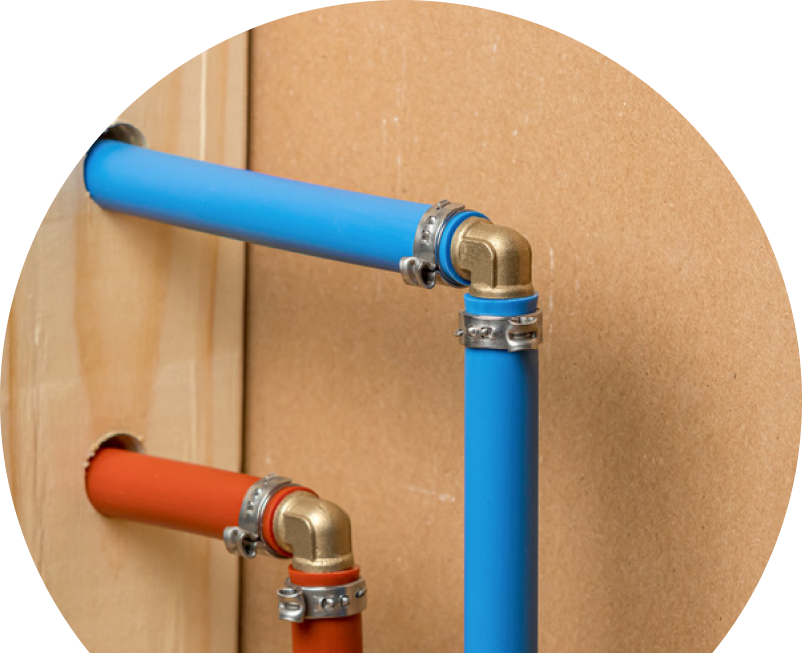 Anchor Home Comfort kitec plumbing system with blue and orange plastic pipes connected by brass fittings and metal clamps, mounted on a wooden panel. Anchor Home Comfort kitec plumbing system with blue and orange plastic pipes connected by brass fittings and metal clamps, mounted on a wooden panel.