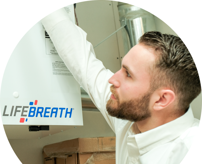 Anchor Home Comfort indoor air quality specialist inspects a Lifebreath ventilation unit related to UV air purifiers, with ductwork and boxes in the background. Anchor Home Comfort indoor air quality specialist inspects a Lifebreath ventilation unit related to UV air purifiers, with ductwork and boxes in the background.