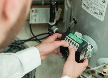 A Anchor Home Comfort technician adjusts the control module on a residential water heater, verifying proper operating settings. A Anchor Home Comfort technician adjusts the control module on a residential water heater, verifying proper operating settings.
